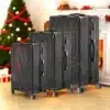 Kolm musta ratastega kohvrit TSA lukuga seisavad jõulupuude ja kingituste taustal, pakkudes elegantset ja turvalist reisilahendust.