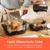 Kuumõhufritüür 4 l klaasaknaga automaatne must, valmistamas maitsvat praekana koos köögiviljadega puidust köögilaual. Taustal kaetud lauanõud.