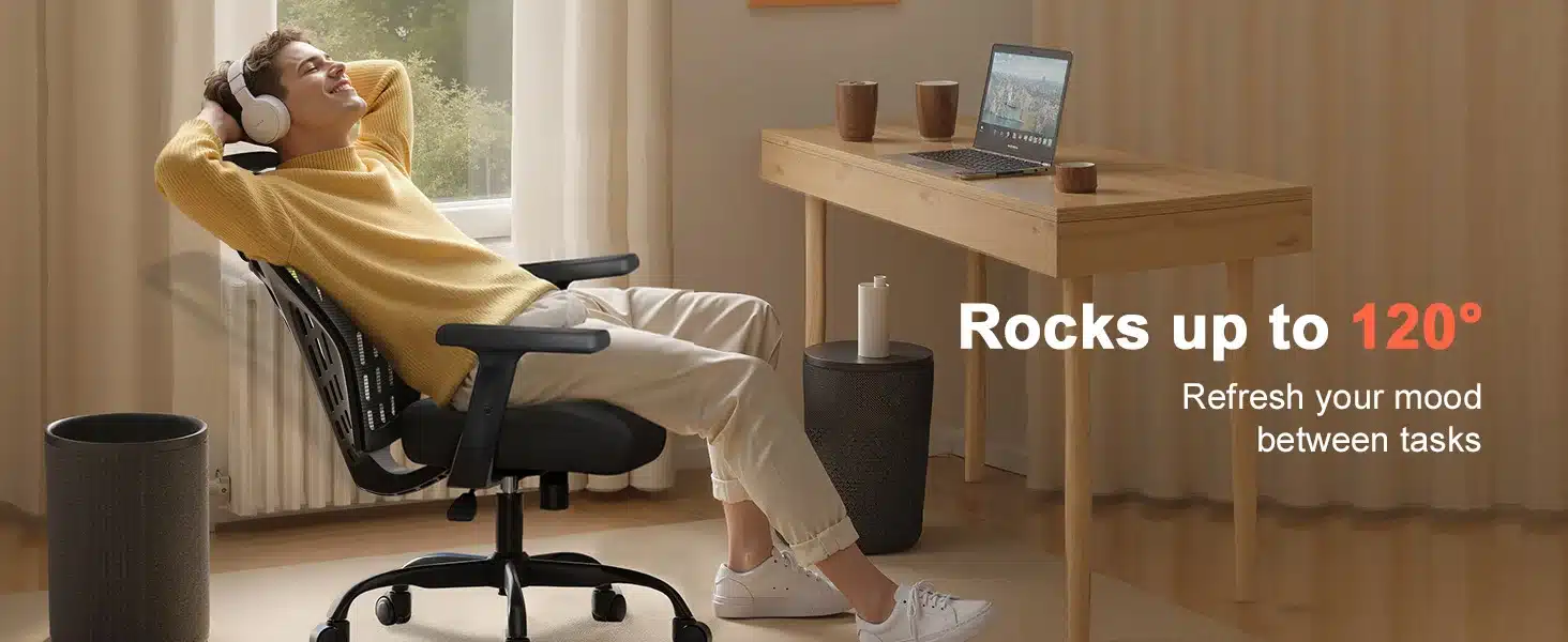Kontoritool ergonoomiline võrkkattega reguleeritavate käetugedega, musta värvi ja seljatoega, mees lõõgastumas toolil, käed pea taga, kõrvaklapid peas, töölaud arvutiga taustal.