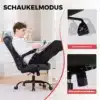 Mänguritool ergonoomiline kiikuvate käetugedega must | E-pood Tootemaailm Inimene istub mustal mänguritoolil, millel on ergonoomiline disain ja kiikuvad käetoed. Tool asub avaras heledas ruumis, valge puitpõrandaga, taustal on nähtav kaasaegne mööbel ja dekoratsioonid.
