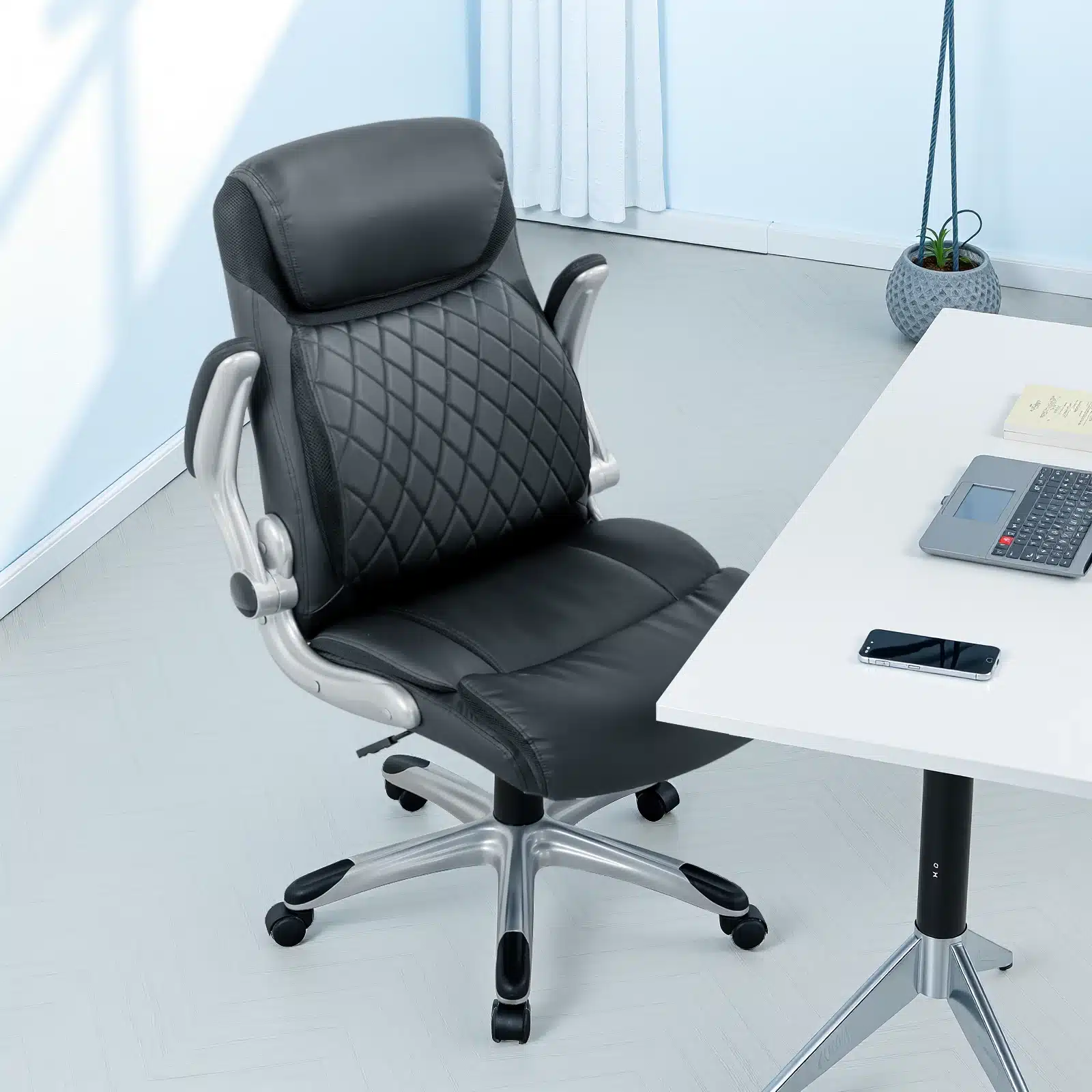 Ergonoomiline kontoritool kõrge seljatoega nahkkattega, mis asub kaasaegses kontori interjööris. Tool on musta värvi, hõbedaste detailidega ja paistab mugavalt paigutatud valge laua kõrval, millel on sülearvuti ja nutitelefon.