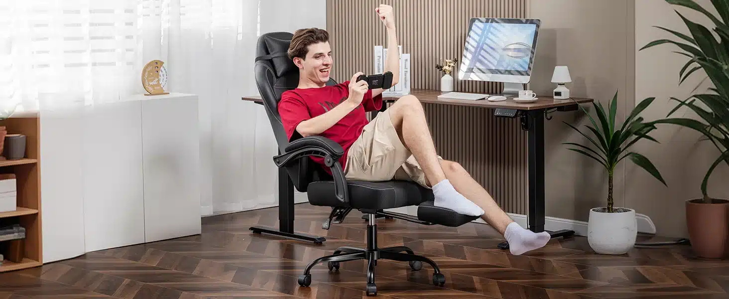 Poiss istub mänguritoolis jalatoega, ergonoomiline ja reguleeritav, mängides mängukonsooliga valges ja beežis sisustatud toas.