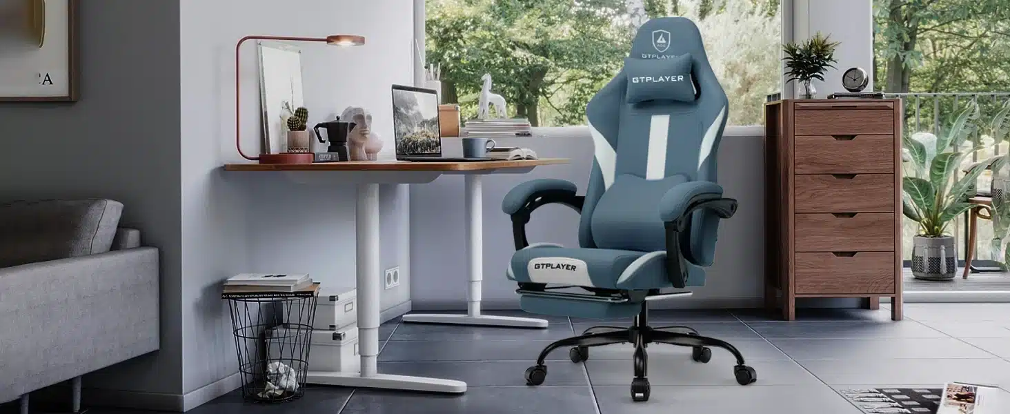 Ergonoomiline arvutitool hingav kangas reguleeritav, sinistes toonides, asetatuna kaasaegses kodukontoris valgusküllase akna kõrval, puidust laud ja kapp taustal.