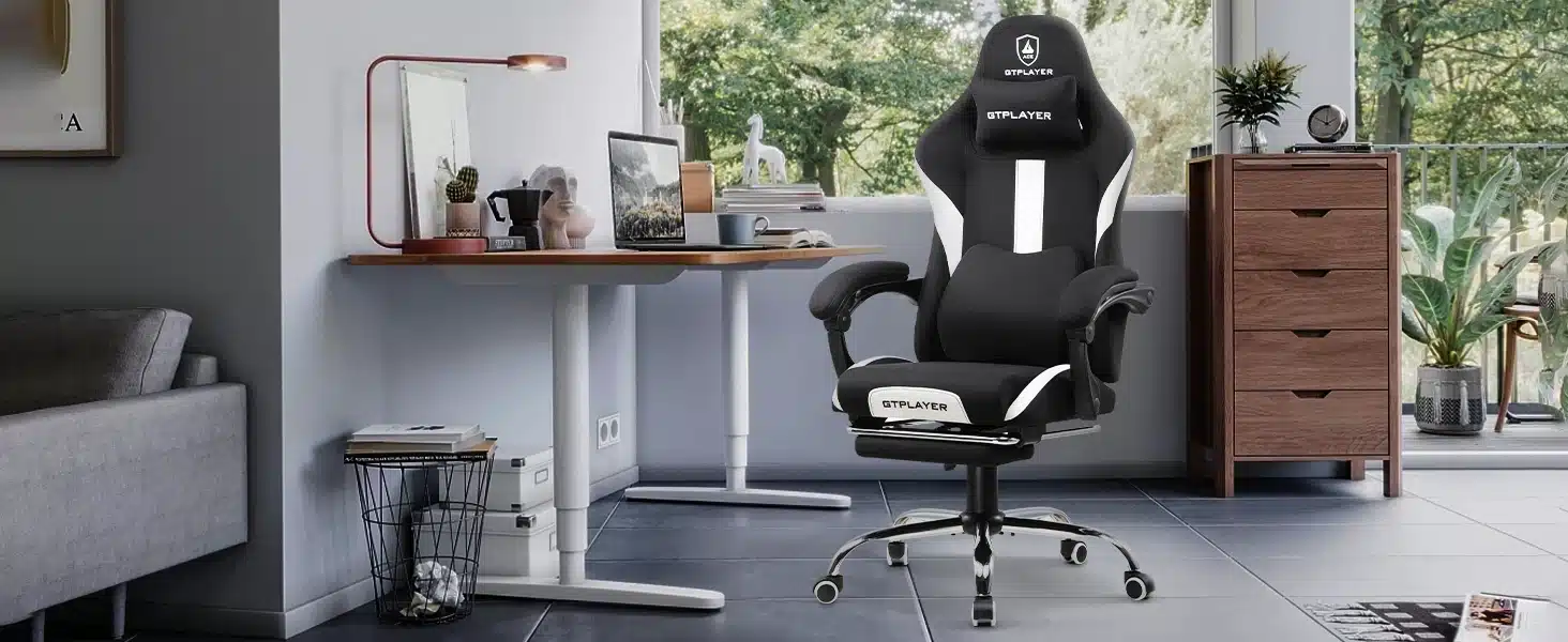 Must ja valge ergonoomiline arvutitool, hingava kangaga ja reguleeritava funktsiooniga, asetatud modernsesse kontoriruumi, millel on puitmööbel ja aknast avanev vaade rohelisse.