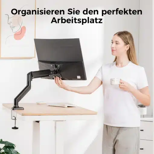 Monitorihoidik 13–32-tollisele ekraanile, reguleeritav | E-pood Tootemaailm Naeratav naisterahvas hoiab kohvikruusi ja reguleerib monitorihoidikut, mis toetab 13–32-tollist ekraani heledal tööpinnal. Taustal on minimalistlik valge sein.