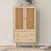 Kummut rotangiga, 2 ust ja 2 sahtlit, 60 cm lai, naturaalse puiduvärvi viimistlusega ning elegantse rotangist uste detailiga heleda seinataustaga ruumis.