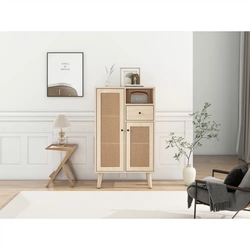 Elutoas asuv kummut rotangiga, 2 ust ja 2 sahtlit, 60 cm lai, elegantse naturaalse viimistlusega, õhulisel valgel taustal. Kapi kõrval paistab pilt seinal ning plant siseruumis, rõhutades kaasaegset ja kodust interjööri.