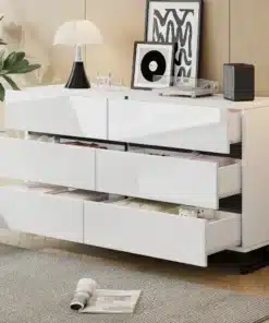 Valge kõrgläikega kummut, millel on kuus avatud sahtlit ja suur mahutavus, asub elegantse elutoa puidust põrandal, ümbritsetuna stiilsetest aksessuaaridest ja kaasaegsest sisekujundusest.