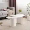 Kohvilaud valge MDF-ga, 100 cm, kaarja disainiga | E-pood Tootemaailm Valge MDF-st kaarja disainiga kohvilaud, 100 cm, paigutatuna stiilsesse elutuppa, mille taustal on hall diivan ja lillad kardinad.
