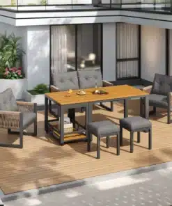 Aiamööbli komplekt 7-osaline ilmastikukindel rotang, mis koosneb laua- ja istumisosadest ning on paigutatud puidust terrassile. Komplekti iseloomustab elegantne hall ja metallik toon, raamitud roostekindlast terasest, ümbruskonnas on tänapäevased valged hooned.