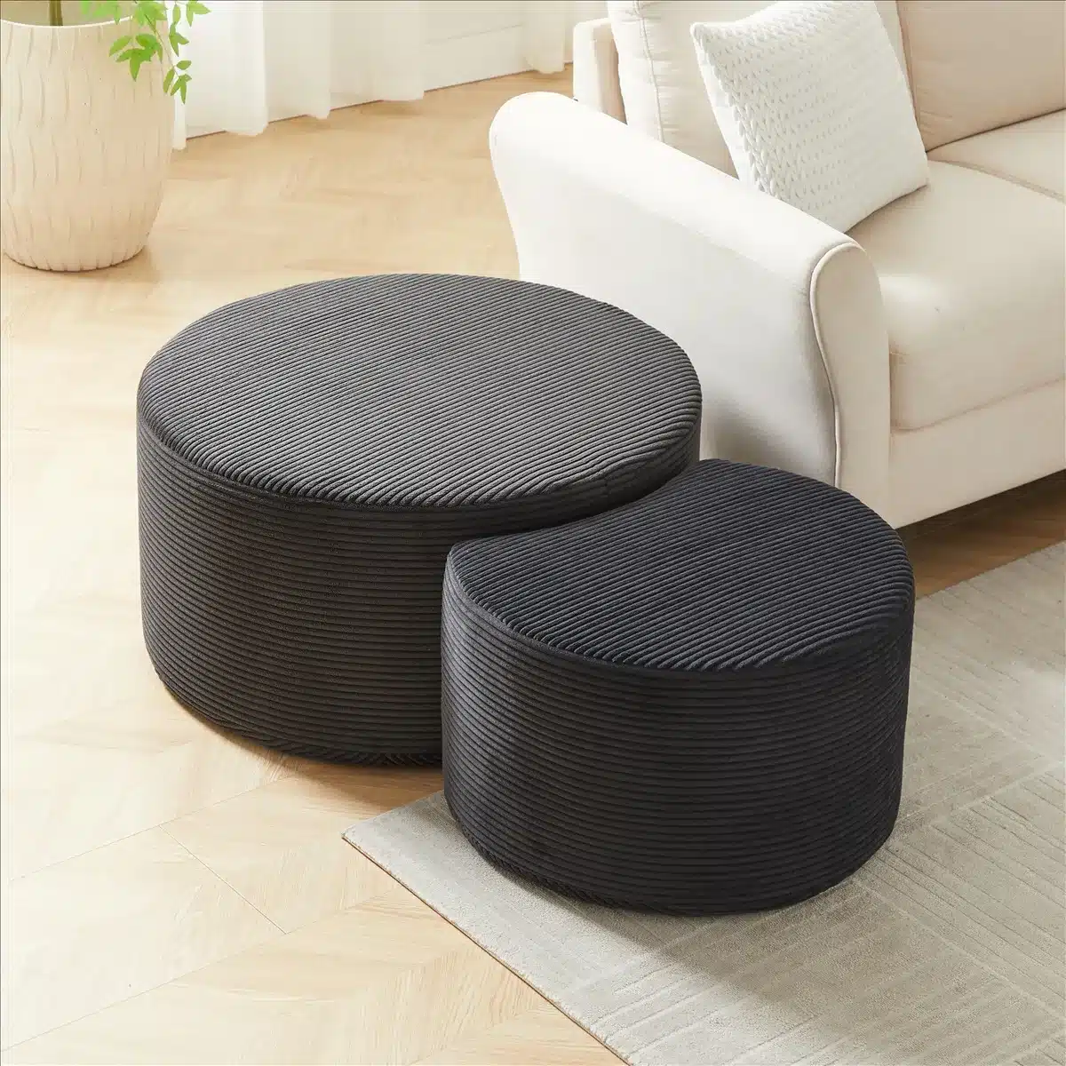 Kaunis diivanilaudade komplekt, mis koosneb kahest ümarast, tumehallist sametkangast lauast, mugavalt paigutatud hele beeži diivani ees. Lauad on modernsed ja elegantsed, sobides ideaalselt igasse elutuppa, helel parkiitud puidust põrandal.