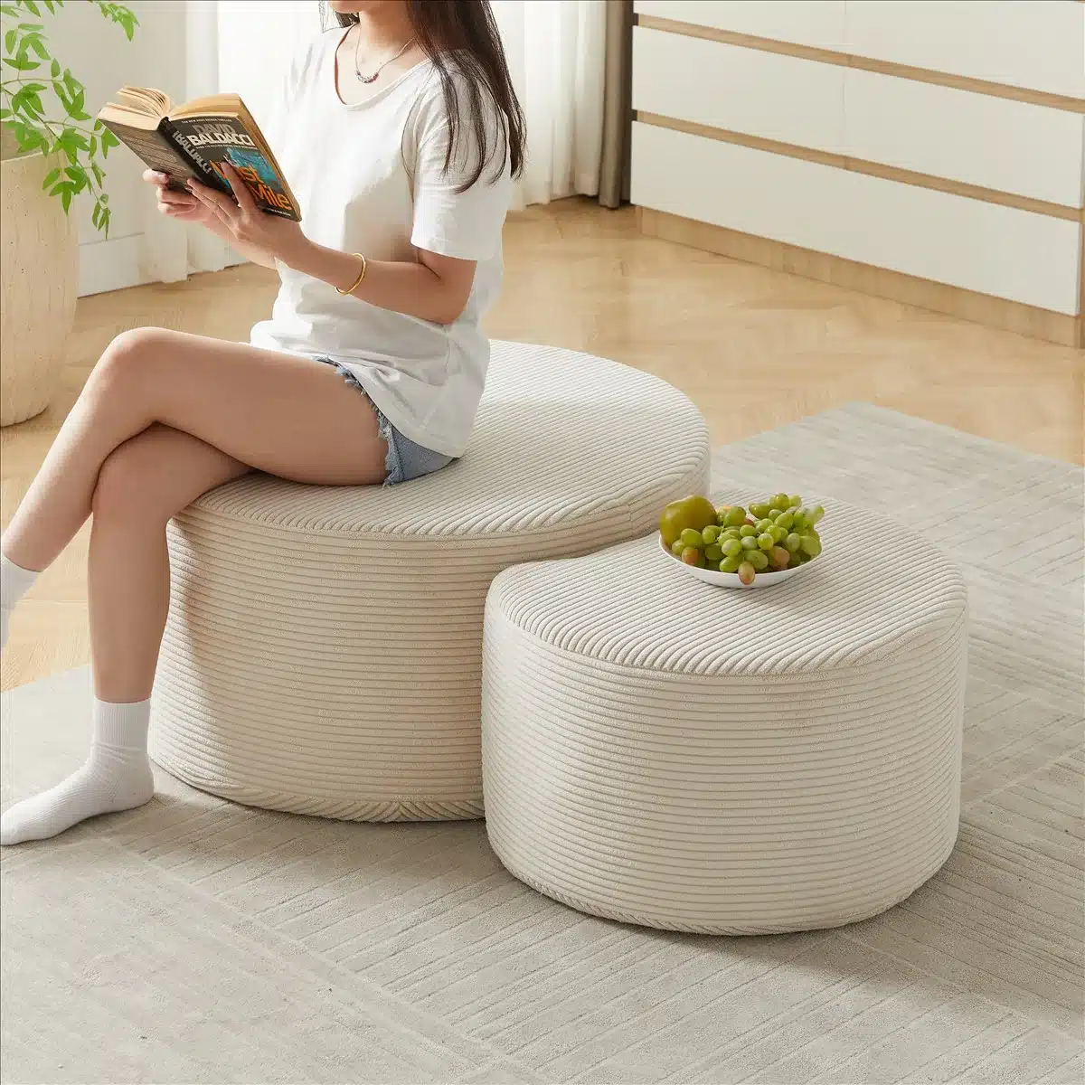 Diivanilaudade komplekt ümarast sametist, 2-osaline, beeži värvi. Vormitud mugavaks istumiseks ja dekoreeritud ruumi keskpunktiks. Taustal hele elutuba, luksuslike detailidega sile parkettpõrand.