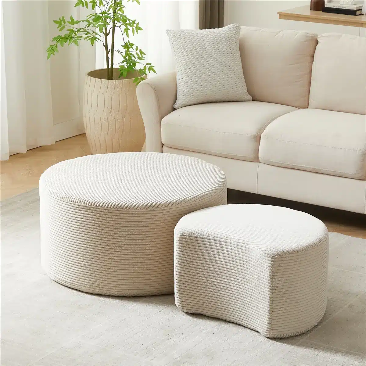 Elegantne diivanilaudade komplekt, mis koosneb kahest ümarast sametist lauast beeži värviga, paigaldatud mugavale elutuppa hele diivani lähedale.