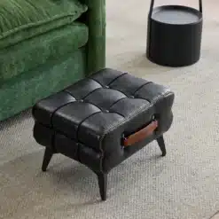 Jalatugi elutoas, mustast nahast polster ja metalljalad, mahukas ja elegantne disain.