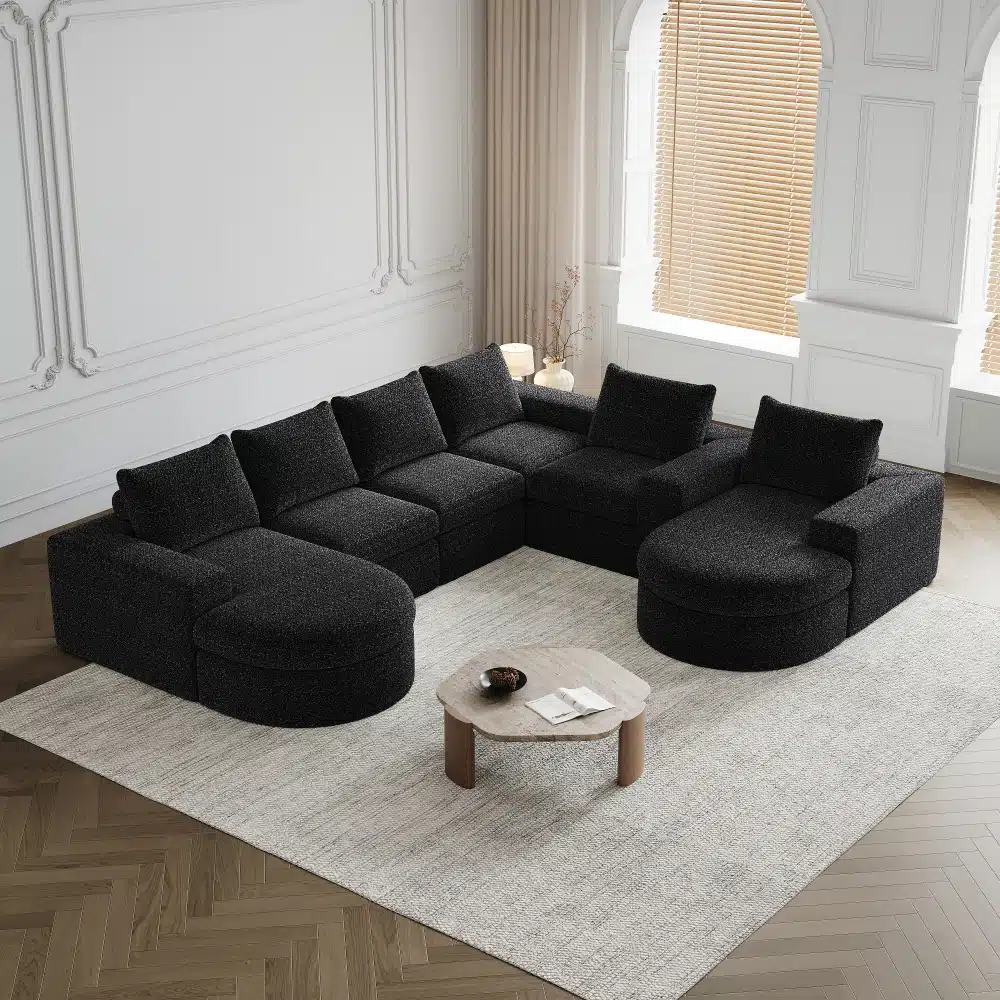 Tume hall chenille kangast nurgadiivan, mis on mugav ja kokkupandav, asetseb elegantselt ruumikas elutoas heledal vaibal koos väikese ümmarguse puidust kohvilauaga. Diivanile langev naturaalne valgus rõhutab selle pehmet ja luksuslikku tekstuuri, pakkudes meeldivat istumiskohta.