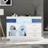 Köögikapp LED-valgustusega, kõrgläike ja 3 sahtliga | E-pood Tootemaailm Valge köögikapp LED-valgustusega, kõrgläike ja 3 sahtliga, mida on kaunistatud kuldsete käepidemetega. Peegeldav viimistlus paistab elegantselt halli seina taustal, lisaks sinine LED-valgus tekitab kaasaegse atmosfääri.
