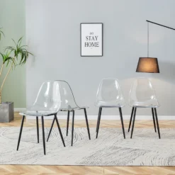 Nelik läbipaistvaid söögitoole mustade metalljalgadega, mis asetsevad modernses elutoas vaibal. Sein, millele on riputatud pilt, ja toataim taustal loovad avara ja stiilse interjööri.