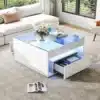 Kaasaegne diivanilaud LED-valgustusega valgendas elutoa interjööri, pakkudes kahel pool praktilisi sahtleid. Looduslik valgus toas, valge pehme diivan ja neutraalne vaip seavad elegantse, kuid funktsionaalse tooni.