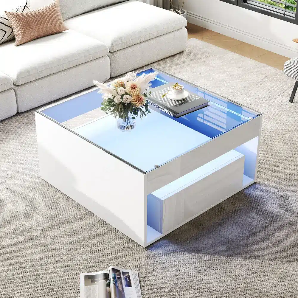 Valge diivanilaud LED-valgustusega, millel on klaasist pealne ja kaks sahtlit, modernses elutoas asuval vaibal.