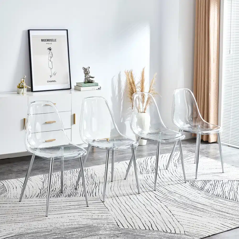 Neli kaasaegset läbipaistvat tooli metalljalgadega, paigutatud elegantsele vaibale heledas toas. Taustal on kapi peal dekoratiivsed esemed ja minimalistlik seinapilt.