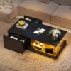 Diivanilaud LED-valgustusega, must, 2 sahtlit, MDF klaas | E-pood Tootemaailm Must diivanilaud LED-valgustusega, millel on kaks sahtlit MDF klaasist pinnaga, asetatud hubasesse elutuppa, kaunistatud lillede ja puuviljadega.