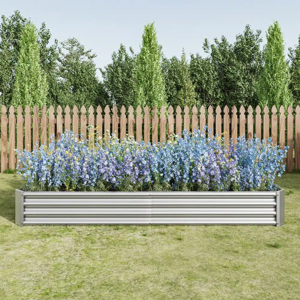 Tõstetud aiapeenar tsingitud terasest, roostekindel, täis värvilisi lilli, paigutatud rohelisele murule puidust aia taustal.