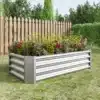 Tõstetud aiapeenar tsingitud terasest 120x60x30 cm | E-pood Tootemaailm Tõstetud aiapeenar tsingitud terasest mõõtmetega 120x60x30 cm, täis rohelisi taimi ja lilli, paigutatud lopsaka muruga aeda puidust tara ees.