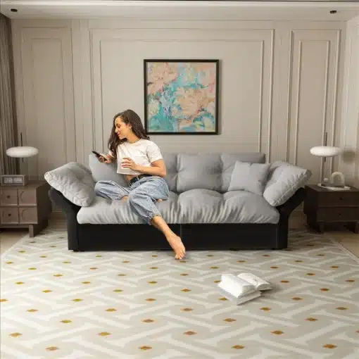 Diivanvoodi 3-in-1, samet, queen-size, 190 cm, | E-pood Tootemaailm Diivanvoodi 3-in-1, samet, queen-size, 190 cm, kauni halli värviga, asub modernses elutoas beeži vaiba peal. Naine istub diivanil, hoides käes puldi ja kohvitassi.
