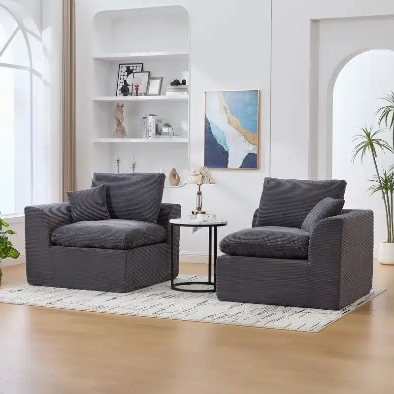 Kahekohaline mooduldiivan koosneb kahest hallist tugitoolist, mis asuvad heledal vaibal valgusküllases elutoas. Diivanil on pehmed ja elegantsed padjad ning kaasas on sobiv väike kohvilaud. Taustal on valged riiulid ja seinal maal. Diivani tume hall värv loob ruumis kaasaegse ja stiilse atmosfääri.