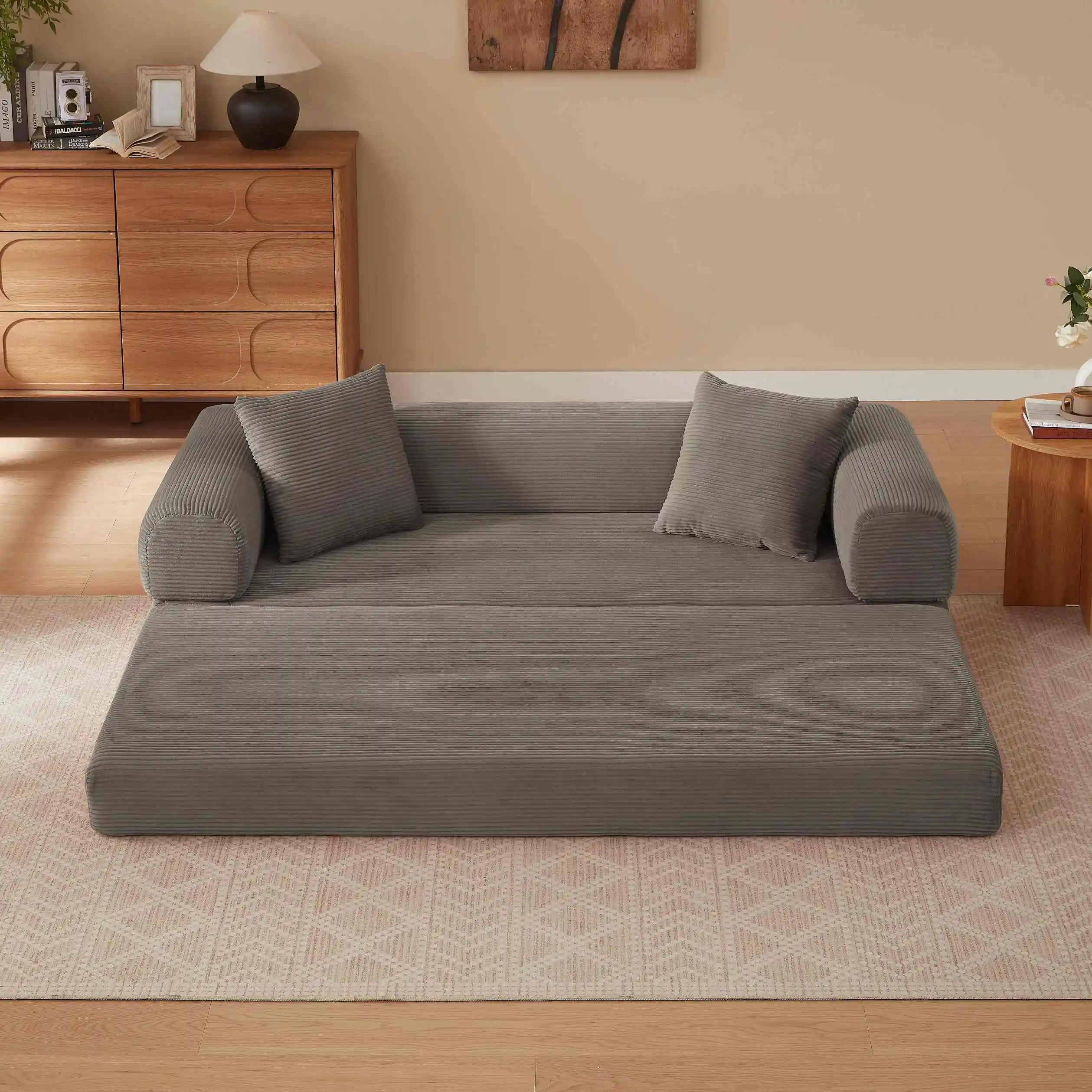 Elegantses elutoas asuv kokkupandav khaki värvi diivanvoodi, valmistatud pehmest sametist, koos kaunistuste ja vaipkattega puidust taustal.