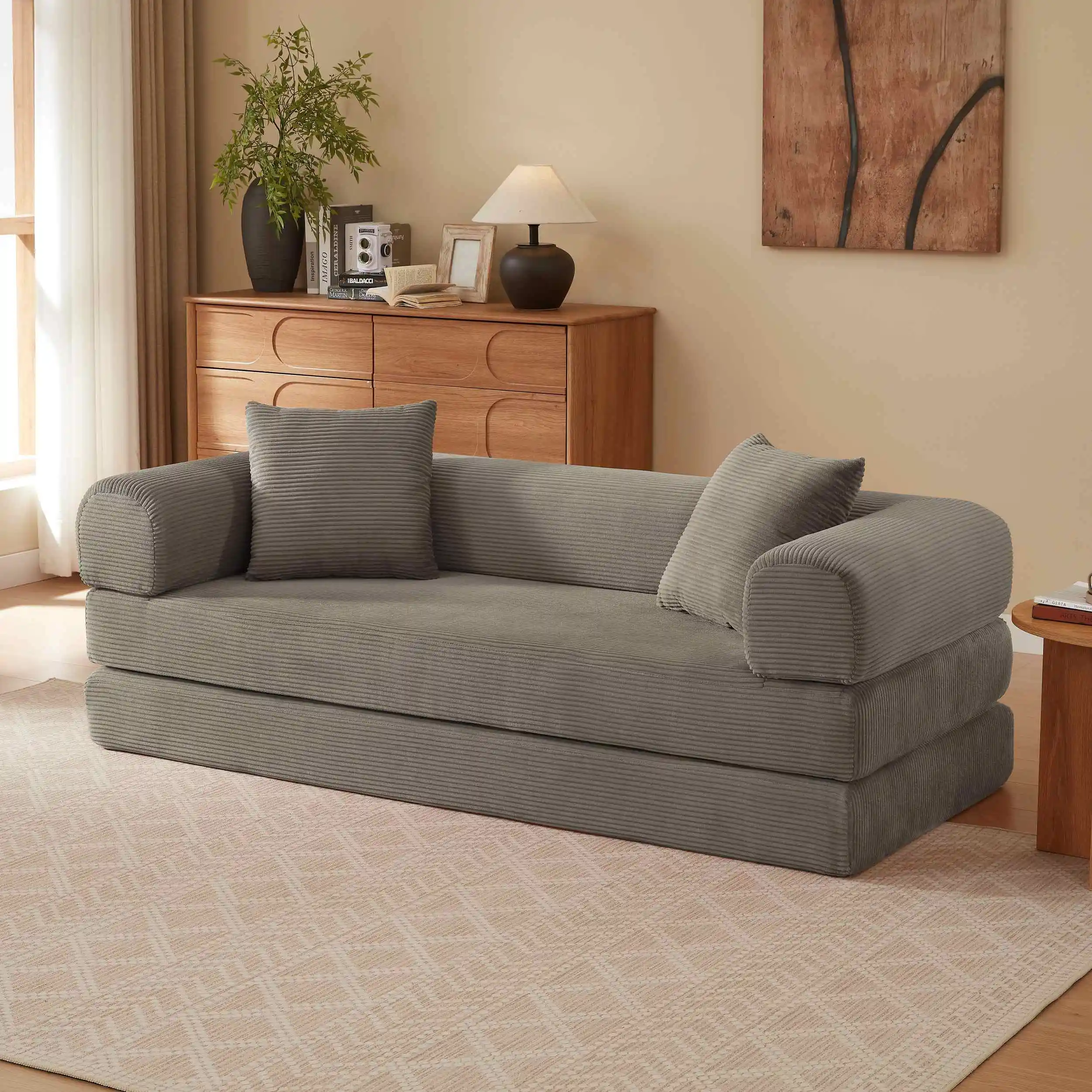 Pehme khaki värvi sametist kokkupandav diivanvoodi, mis paikneb hubases elutoas heledal vaibal ja puidust mööbliga. Diivan on minimalistliku disainiga, ideaalne kaasaegses kodus.
