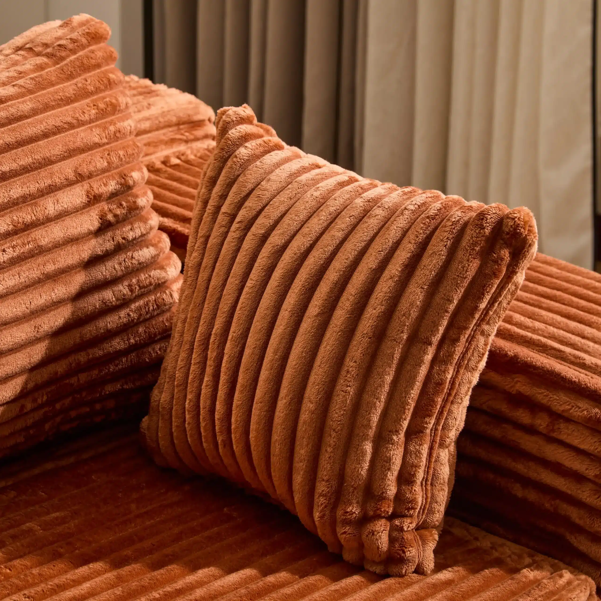 Vaakumpakendatud mooduldiivan koos pehmete sametist patjadega, mis on soojas oranžis toonis ja tekstuurse disainiga, sobitudes elegantse elutoa sisustusega.