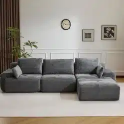 Moodul nurgadiivan sametist hall, 3-kohaline koos patjadega, asub elegantse valge seinaga elutoas, mille taustal on kunstiteosed ja toataimed.