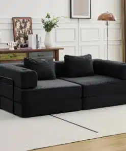 Kahe-kohaline must veluurist diivanvoodi elegantses elutoas, taustal valge paneelsein ja rustikaalne puidust kapp koos dekoratiivsete elementidega.
