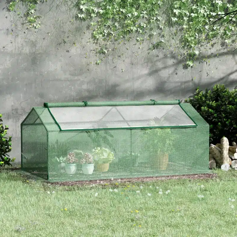 Roheline kasvuhoone aknaga aiamaal, veekindel kaitse taimedele, mõõtmetega 180x90x70 cm, asetatud rohelisele murule ja taustal rohelised põõsad.