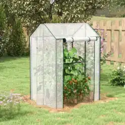 Valge kasvuhoone kahekordse uksega aias, mis on tuulekindel ja mõõtmetega 100x80x150 cm. Kasvuhoone sees kasvavad tomatitaimed, ümbritsetud rohelisest murust ja lilledega.