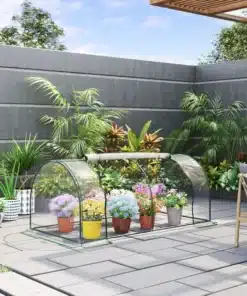 Kauni Kasvuhoone uksega, 200x100x80 cm aiataimedele, mis asub terrassil. Kasvuhoone on valmistatud läbipaistvast plastikust ja metallist raamiga, hoides värvilisi potitaimi tänavakividega kaetud taustal.