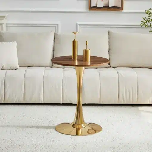 Ümmargune diivanilaud 60 cm, valmistatud pähklipuu MDF-st ja seisab elegantsel kuldsest metallist jalal, valges elutoas beežil vaibal. Laua peal on kaks kuldset dekoratiivset eset.