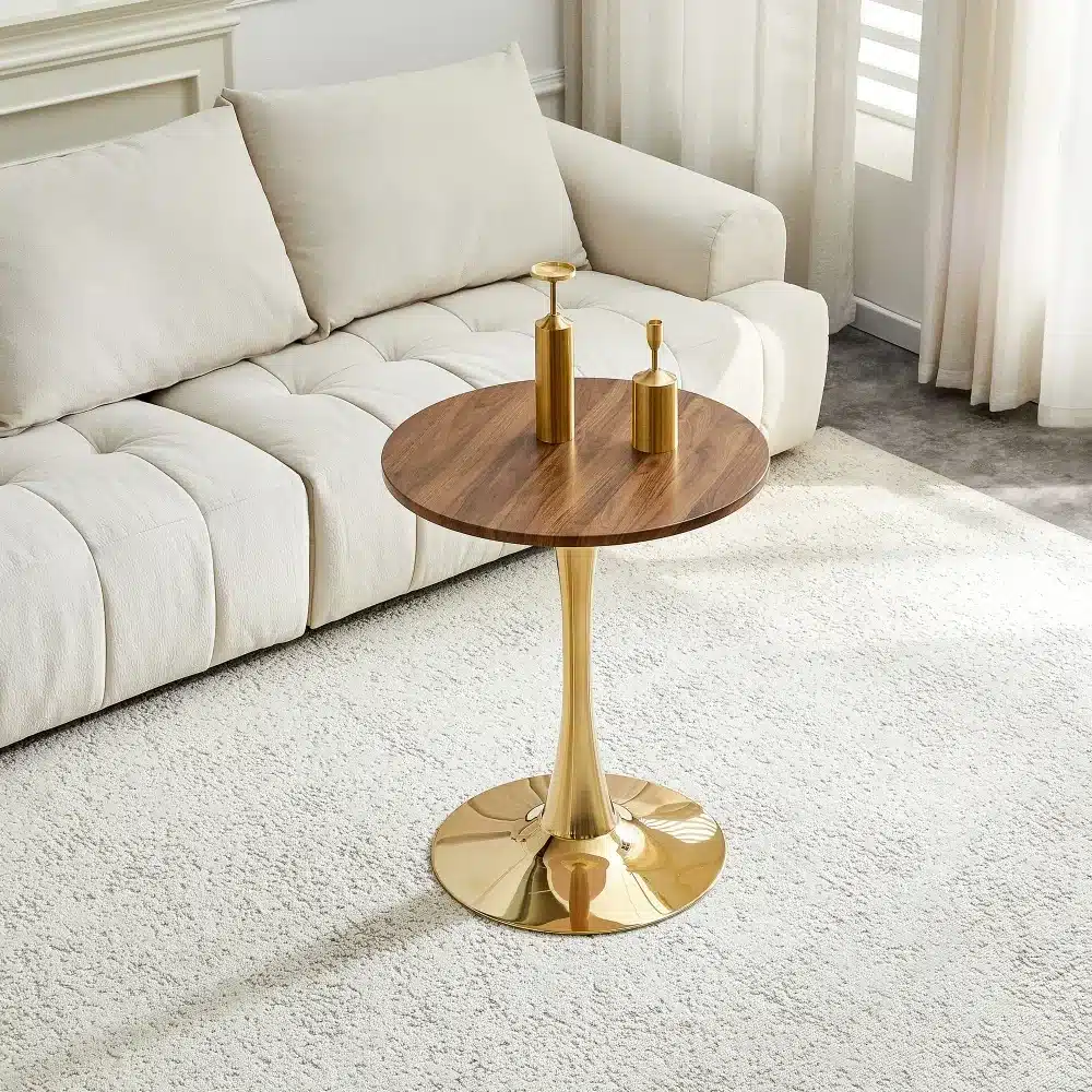 Elegantne ümmargune diivanilaud diivanipadjaga taustal, diameetriga 60 cm, valmistatud pähklipuu MDF-st ja kuldsete metallist jalgadega.