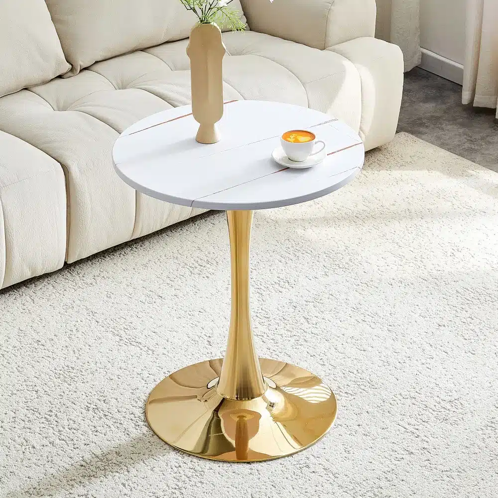 Elegantne ümmargune diivanilaud, 60 cm läbimõõduga, valmistatud pähklipuu MDF materjalist. Laua kuldne jalg loob stiilse kontrasti heleda vaiba ja kreemja diivani taustal. Laua peal on valge kohvitass ja dekoratiivvaas.