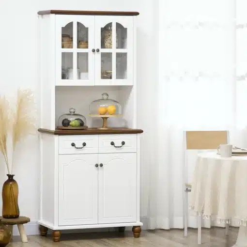 Valge köögikapp klaasuste ja kahe sahtliga | E-pood Tootemaailm Valge köögikapp klaasuste ja kahe sahtliga, mis on asetatud valgusküllasesse ruumi heleda puidust põrandaga. Kapp on elegantse disainiga, varustatud tumeda puidust lauaplaadi ja messingist käepidemetega.