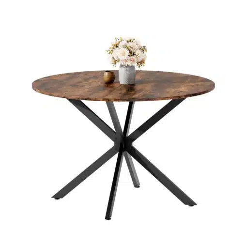 Ümmargune söögilaud 120 cm vintagepruun. Laual on mustad metalljalad ja sellel on lillevaas kimpude ja kuldse dekoratiivnõuga. Taust on valge ja minimalistlik.