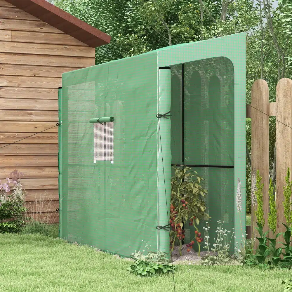 Roheline kasvuhoone UV-kaitsega, kahe ukse ja aknaga, mõõtmetega 200x80x200, asub puitsõidutee kõrval aias, taustal on näha aiataimi ja puid.