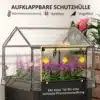 Kõrge aiapeenar kasvuhoone katte ja äravooluavadega | E-pood Tootemaailm Kõrge aiapeenar musta raami ja läbipaistva kasvuhoone kattega. Peenar on täidetud roosade lilledega ning katel on avatud, et näidata selle tugevust ja soojuse säilitamise omadusi.