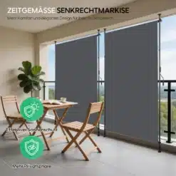 Terrassi vertikaalne markiis antratsiit, käsivändaga 150x270, paigaldatud rõdule. Markiis on antratsiidi värvi ja tagab tõhusa päikesekaitse ning privaatsuse. Kõrval on puidust terrassimööbel ja roheline toataim, taustal avaneb vaade rohelisele maastikule.