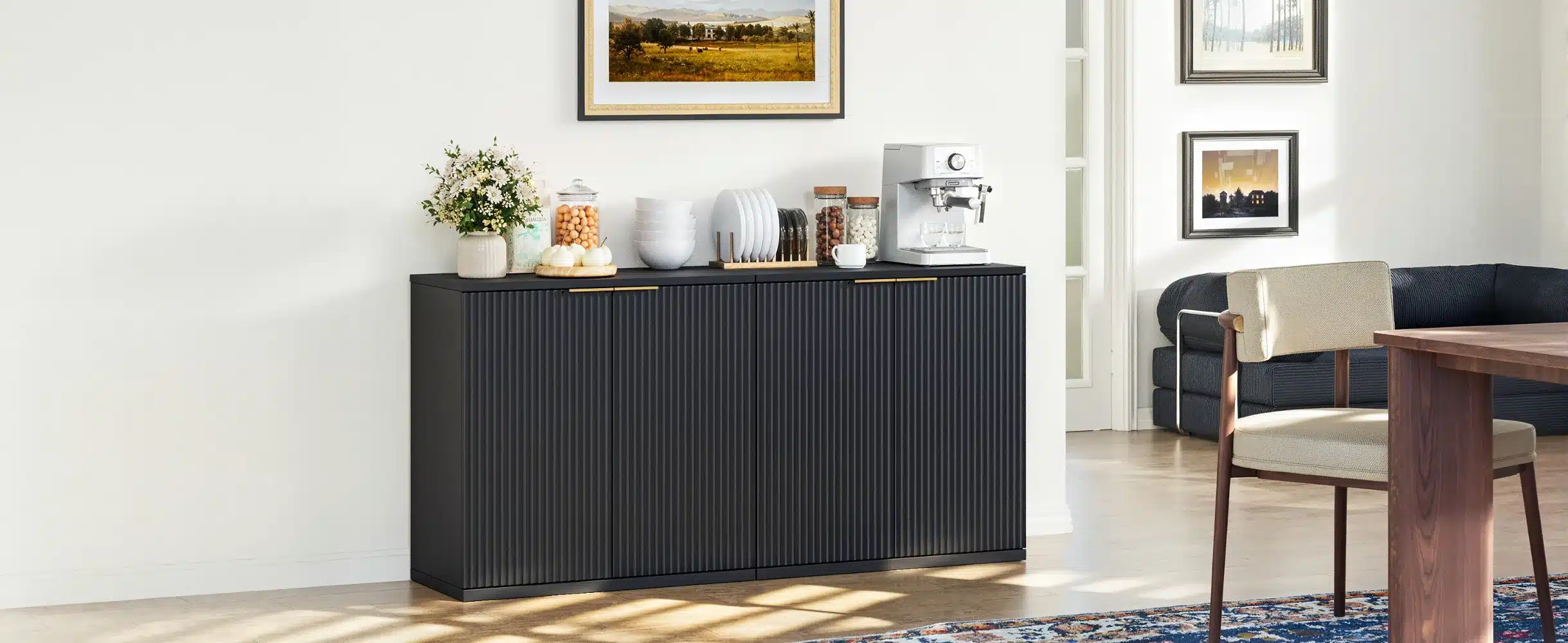 Stiilne Kapp musta puidu imitatsiooniga, volditud uks, asub elutoas valgel taustal, mille peal on dekoratsioonid ja espressomasin.