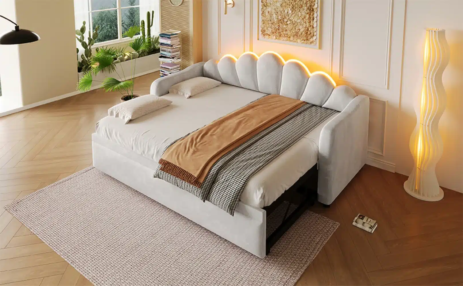 Polsterdatud lahtikäiv voodi LED-valgustusega 90x200 cm, heleda pehme kangaga ja kaasaegse disainiga. Voodi asetub elegantselt heledal puidust põrandal hästivalgustatud toas, mille taustal on sisekujunduselemendid ja elutaimed.