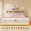Polsterdatud voodi 180x200 cm, LED ja USB-C laadimine | E-pood Tootemaailm Elegantne polsterdatud voodi 180x200 cm, millel on kaasaegsed LED tuled ja sisseehitatud USB-C laadimisport. Voodi asub neutraalsetes toonides magamistoas, selle taustal on minimalistik seinakunst ja kella näit.