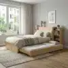Voodi panipaigaga 90x200 cm, väljatõmmatav lisaosa | E-pood Tootemaailm Heledast puidust voodi panipaigaga 90x200 cm, millel on väljatõmmatav lisaosa. Voodi asub valgusküllases toas, mille tapeet on heledat värvi ning aknast paistavad rohelised puud. Voodi kõrval on praktiline raamaturiiul ja voodi ääre peal on ruumikad sahtlid.