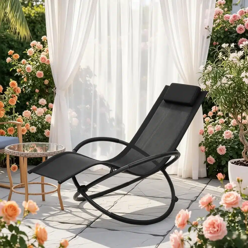 Elegantne must kiikuv lamamistool päikselisel terrassil, ümbritsetud rooside ja valgete kardinatega.